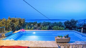 Ein Schwimmbecken mit Blick auf das Meer und Berge im Hintergrund.