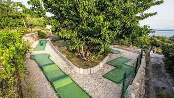 A golf course with multiple green areas and a large tree in the center.
