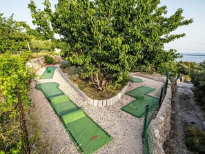 Un camp de golf amb diverses zones verdes i un arbre gran al centre.