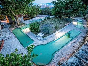 Un campo de mini golf con varios hoyos, rodeado de grava y vegetación.