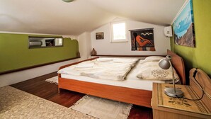 Un dormitorio con cama de madera, una mesita de noche, una lámpara, un espejo y una ventana.