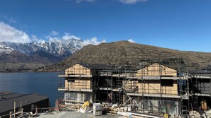 A building under construction with a mountainous backdrop and a body of water.