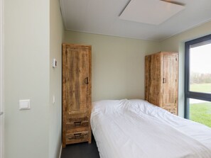 Une chambre à coucher avec un lit, deux armoires en bois, une fenêtre et un interrupteur sur le mur.