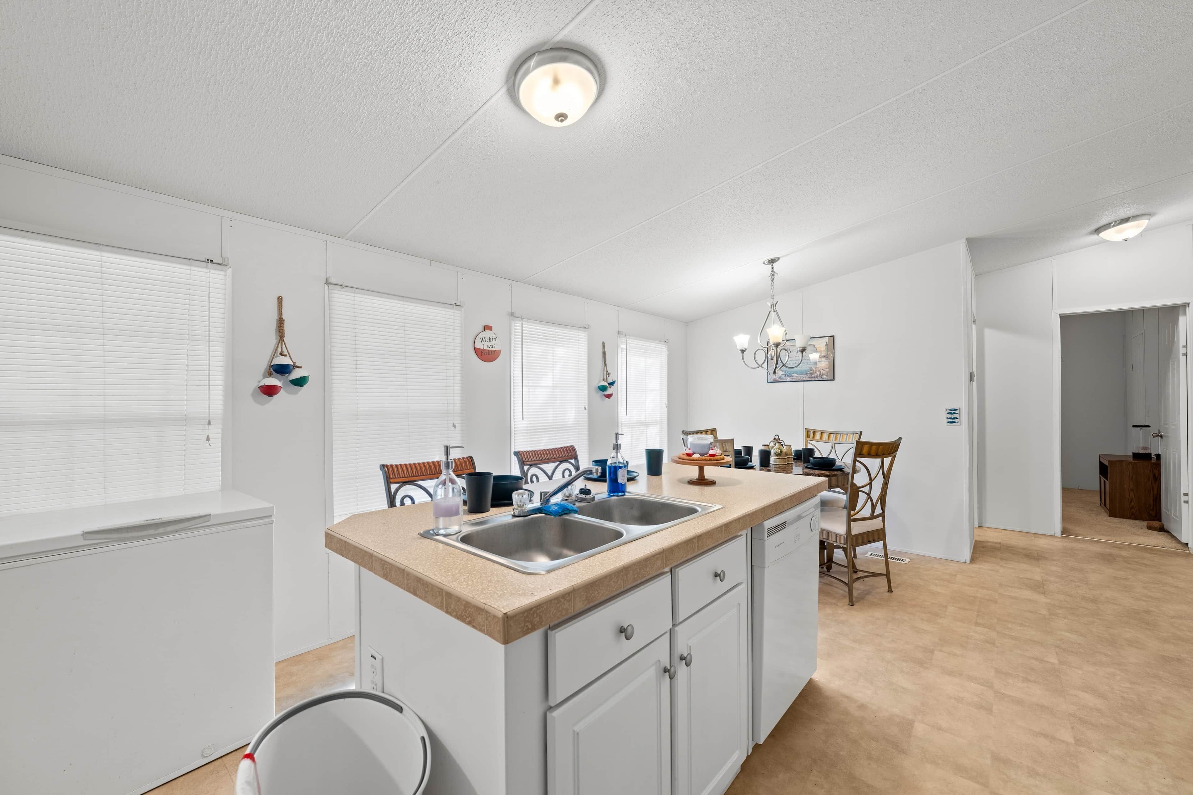 A kitchen with a central island, white cabinetry, and a dining area with chairs and a table.