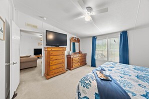 Ein Schlafzimmer mit einem Bett, einem Schminktisch, einem Fernseher und einem Deckenventilator.