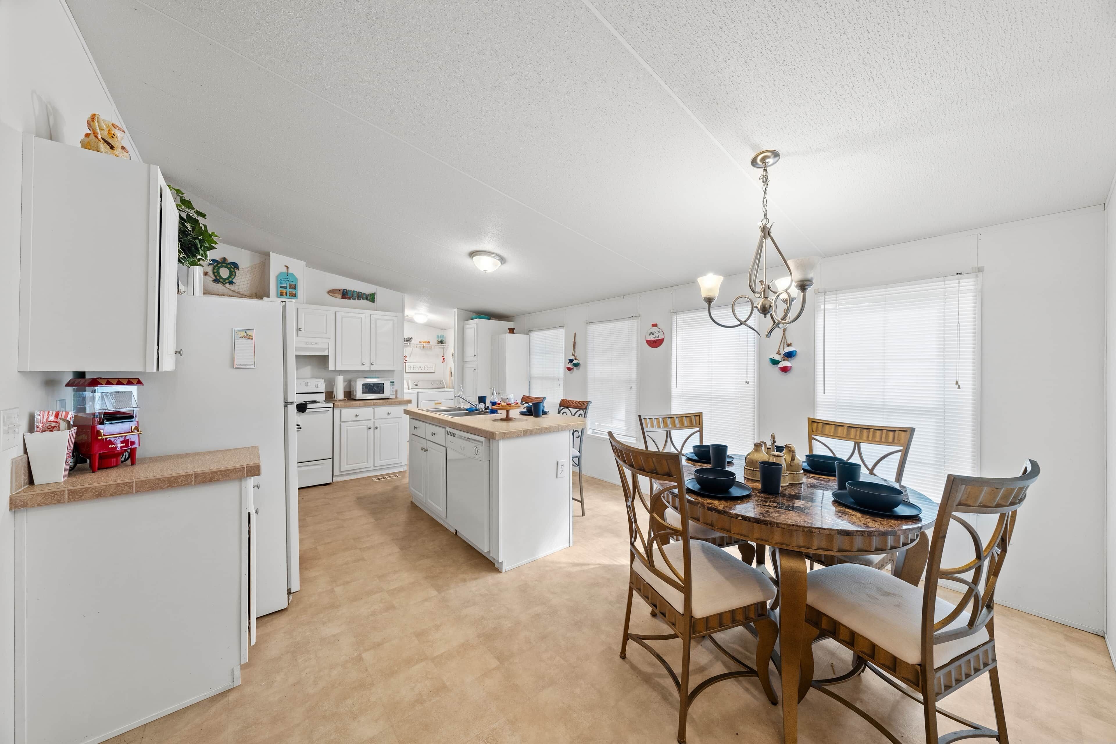 A modern kitchen with white cabinetry, a central island, and a dining area with a round table and chairs.