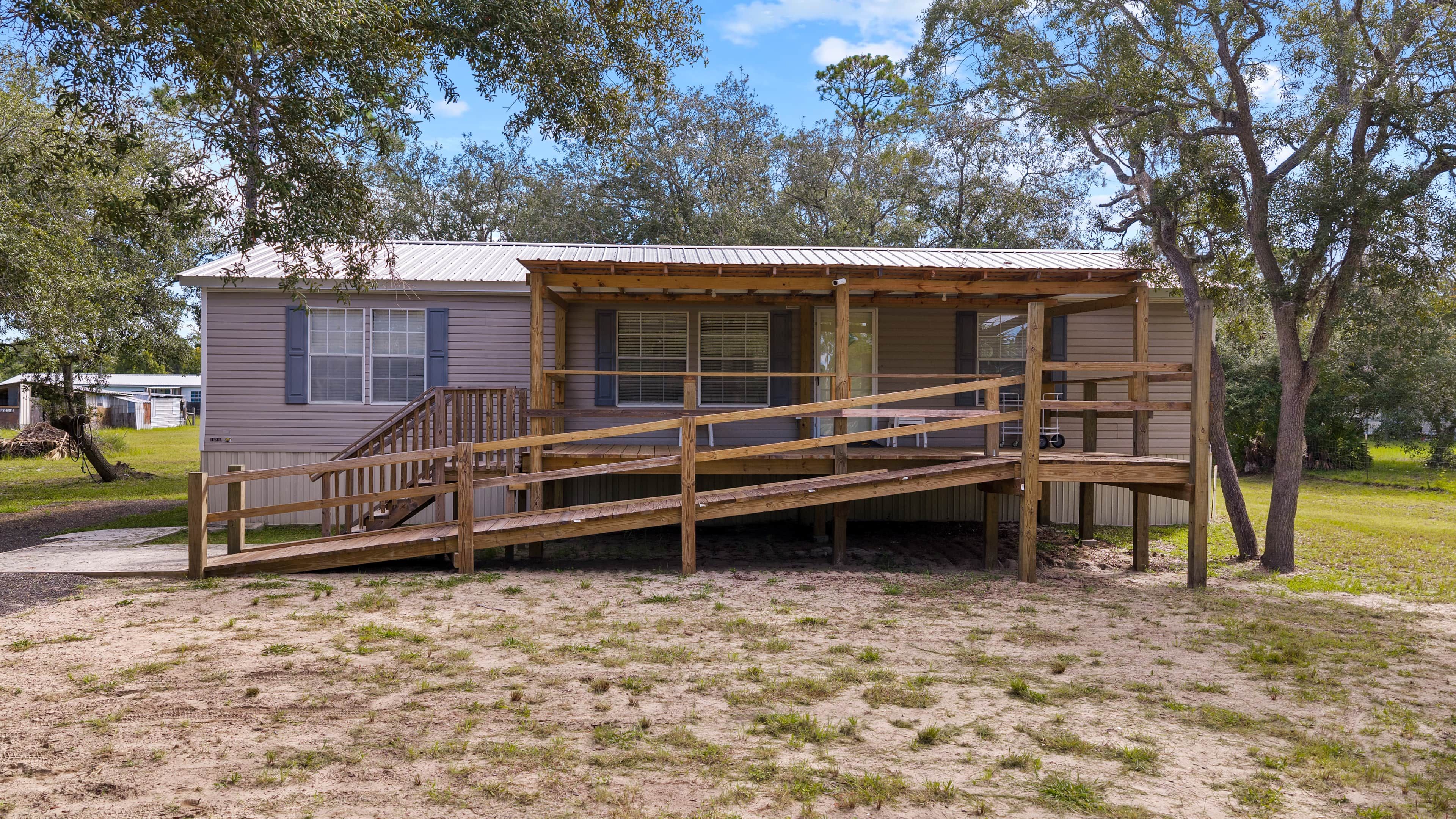 A single-story wooden structure with a porch and a staircase leading to a covered area.