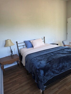 A bedroom with a bed, a nightstand, a lamp, and a chair. - Cozy 1-bedroom cabin in beautiful Kelso with AC (Kelso)