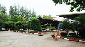 A gated parking area with a covered structure, trees, and a stop sign.