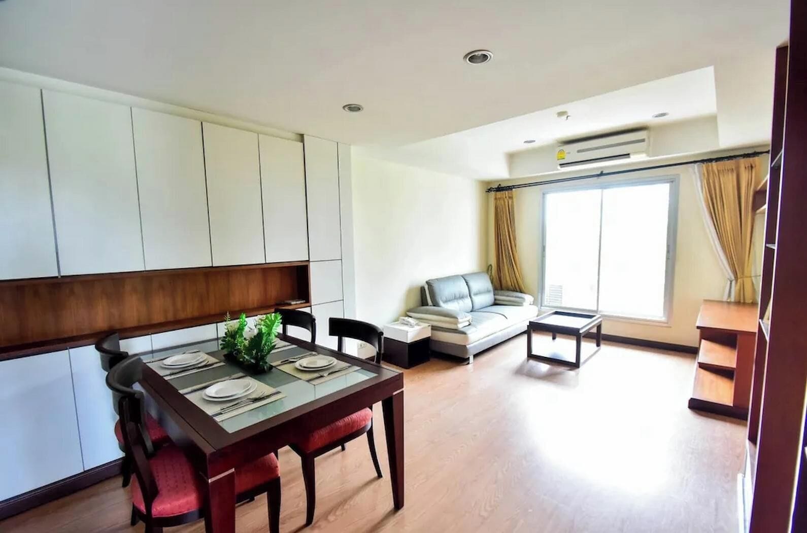 Una sala de estar moderna con comedor, sofá y un ventanal grande.