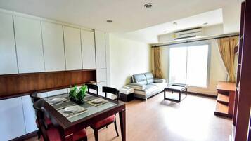 Una sala de estar moderna con comedor, sofá y un ventanal grande.