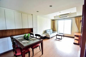 Una sala de estar moderna con comedor, sofá y un ventanal grande.