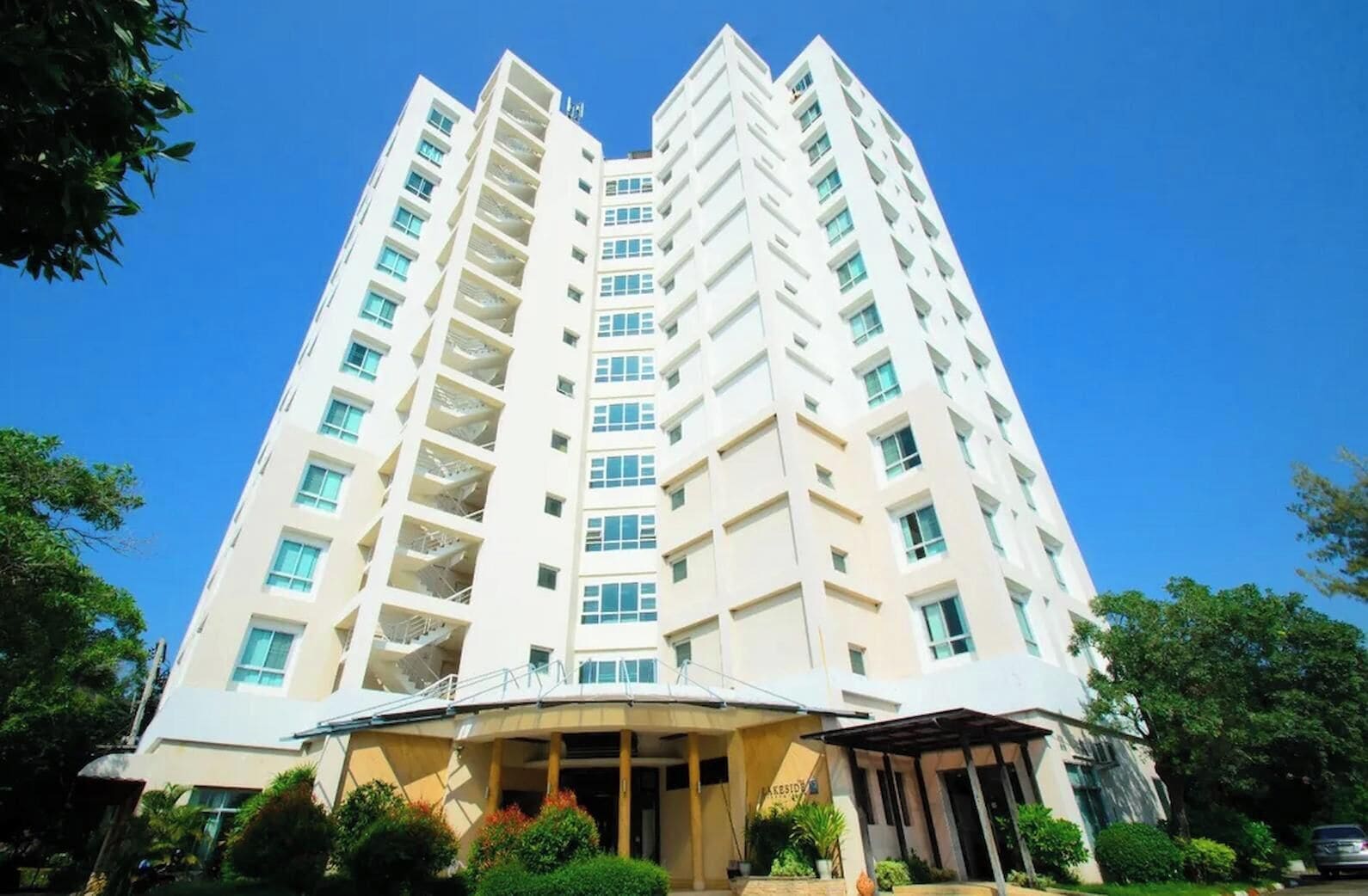 Un edificio residencial de varios pisos con fachada plana, balcones y un área de entrada cubierta.