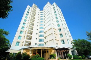 A multi-story residential building with a flat facade, balconies, and a covered entrance area.