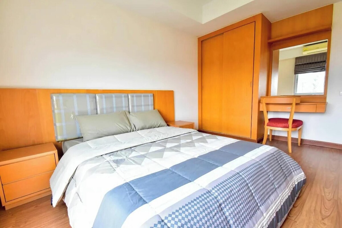 Un dormitorio con cama, mesita de noche, silla, armario y espejo.