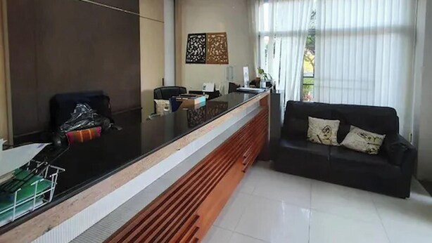 A reception area with a counter, a sofa, and a window with blinds.