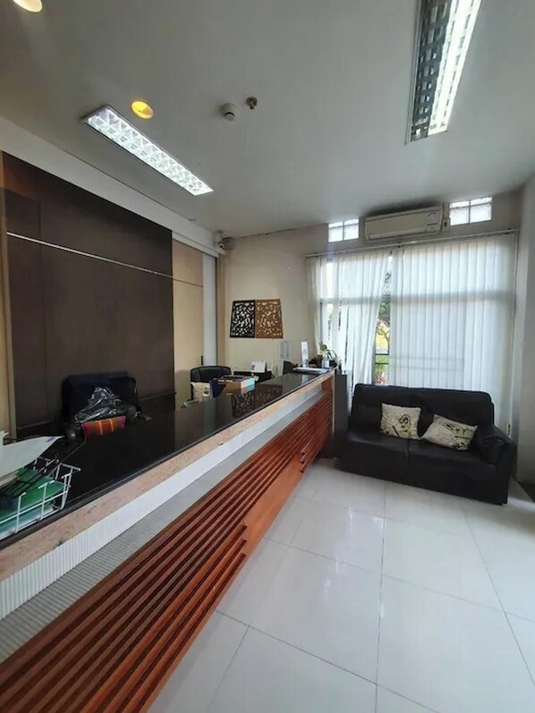 A reception area with a counter, a sofa, and a window with blinds.