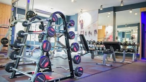 Ett gym med utrustning för styrketräning, inklusive en knäböjsställning och hantlar.