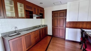 A kitchen with wooden cabinets, a granite countertop, a sink, and a door leading to another room.