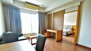 A hotel room with a desk, chair, bed, and a sliding door closet.