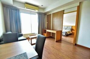 A hotel room with a desk, chair, bed, and a sliding door closet.