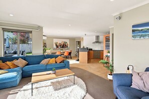 A modern living room with a blue sofa, a coffee table, and a fluffy rug. - Location Plus Nelson family getaway (Nelson)