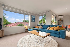 A modern living room with a blue sofa, a wooden coffee table, and a white shag rug.
