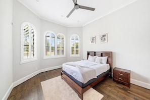 A bedroom with a large bed, a nightstand, and three arched windows. - Houston’s Private Estate Venue | Weddings & Events (Houston)