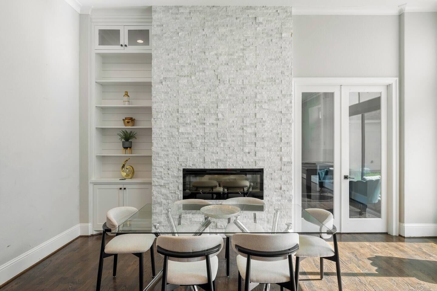 A modern interior with a fireplace, glass dining table, and chairs.