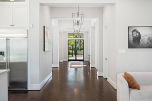 A spacious hallway with a modern kitchen, a dining area, and a living room with a sofa and a framed picture on the wall. - Houston’s Private Estate Venue | Weddings & Events (Houston)