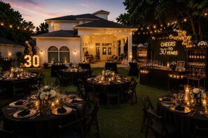 An outdoor dining area with round tables set for a celebration, a bar with a 'Cheers 30 Years' sign, and a large illuminated number '30' sign. - Houston’s Private Estate Venue | Weddings & Events (Houston)