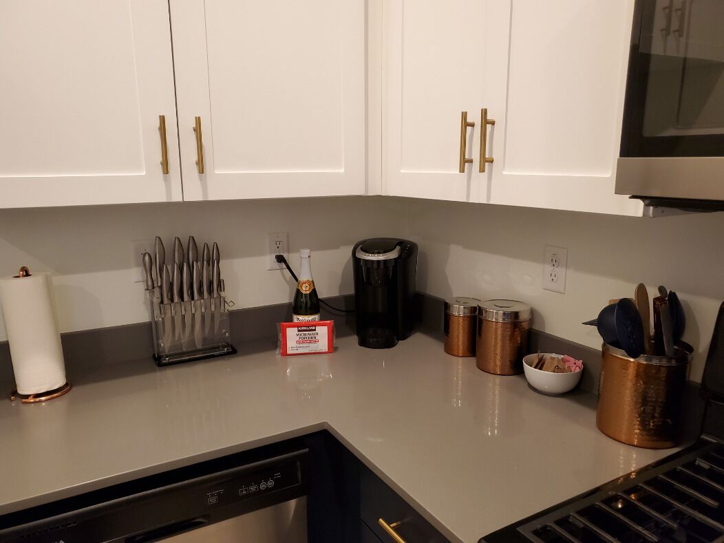A kitchen with white cabinets, a coffee maker, utensils, and a dishwasher.