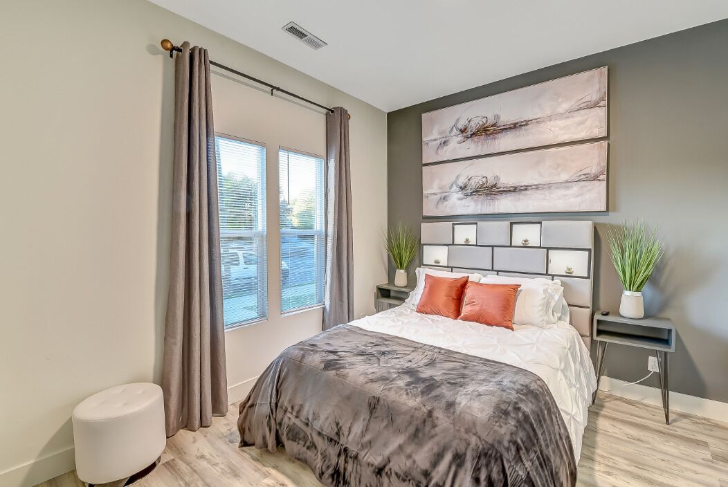 Ein modernes Schlafzimmer mit einem großen Bett, Blick ins Freie und einem Wandbild.