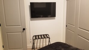 A room with a flat-screen TV mounted on the wall, a small metal stool, and a dark-colored sofa. - Delightful Home with W&D and Office in Salt Lake City (Salt Lake City)