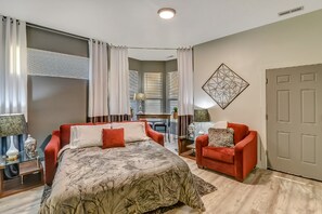 A bedroom with a large bed, a red sofa, a desk, and a chair.