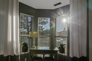 Une pièce d’angle comprenant un bureau, deux chaises, une lampe et deux plantes en pot.