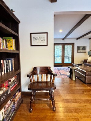 A room with a wooden chair, a bookshelf, a framed picture on the wall, and a view through a door. - Private 7-Acre Retreat w/Brook, Near Hike & Ski (Townshend)