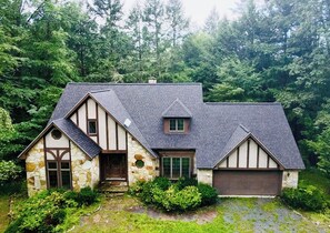 A two-story house with a stone facade, a sloped roof, and a garage. - Private 7-Acre Retreat w/Brook, Near Hike & Ski (Townshend)
