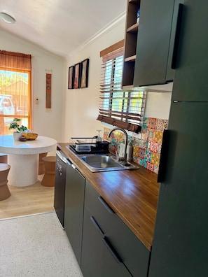 Una cocina con una mesa redonda, lavavajillas integrado y un salpicadero colorido.
