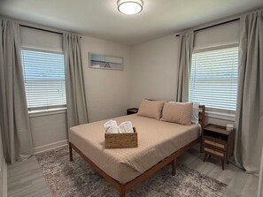 Ein Schlafzimmer mit Bett, Vorhängen, einem Nachttisch und einem Bild an der Wand.