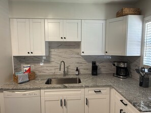 A kitchen with white cabinets, a granite countertop, a stainless steel sink, and a coffee maker. - Sunny South Tampa Hideaway - Palma Ceia - 2BR (Tampa)