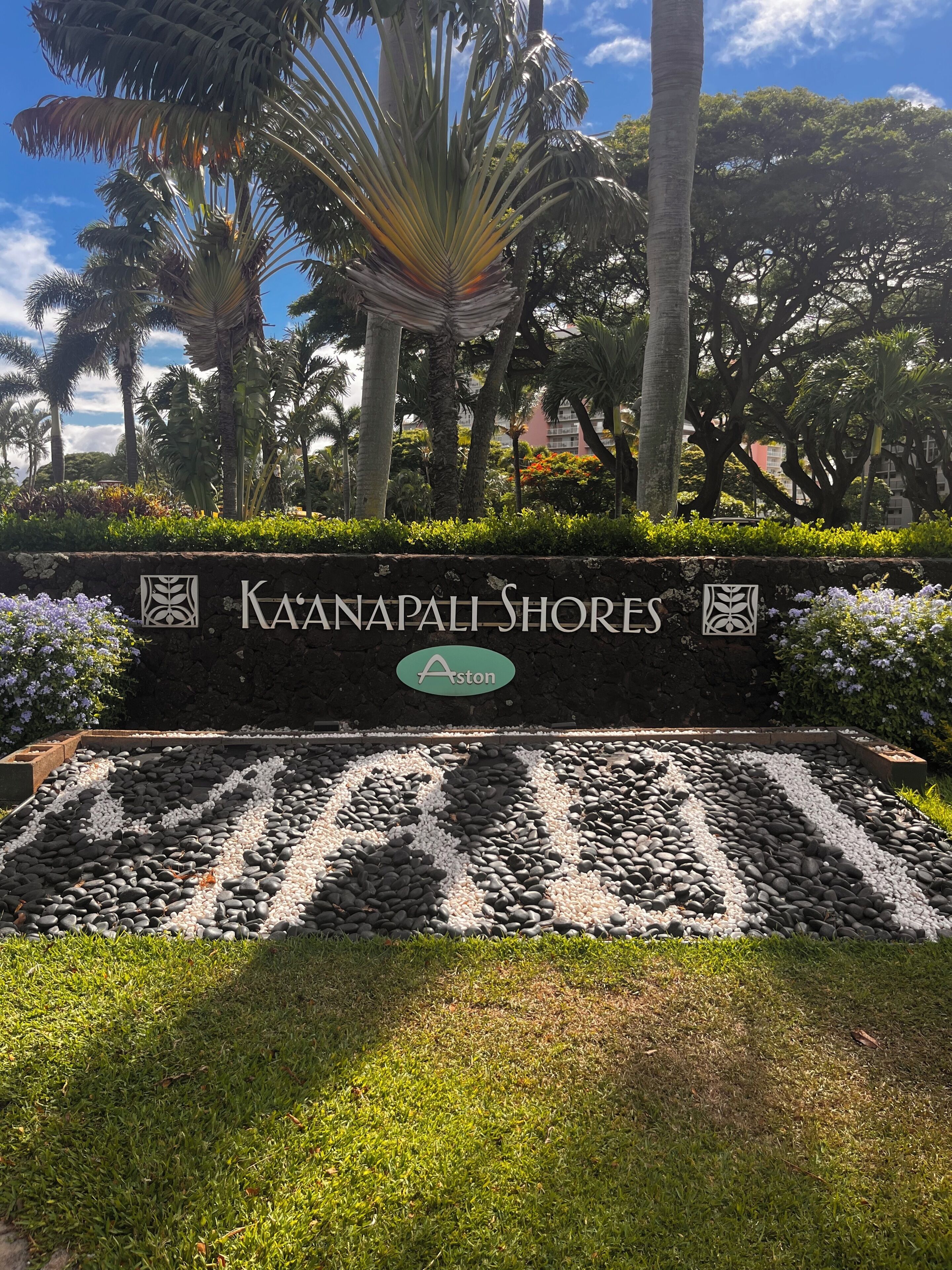 Une enseigne pour Kaanapali Shores, avec son logo, entourée d’un espace paysager agrémenté de rochers et de verdure.