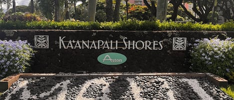 A sign for Kaanapali Shores with a logo, surrounded by a landscaped area with rocks and greenery.