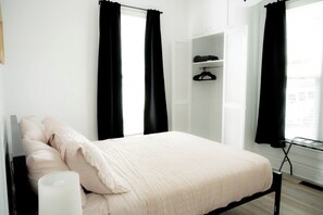 A bedroom with a bed, a wardrobe, and a window with curtains.