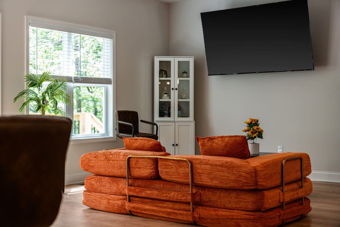 A living room with a sofa, a cabinet, a TV, and a window with blinds.