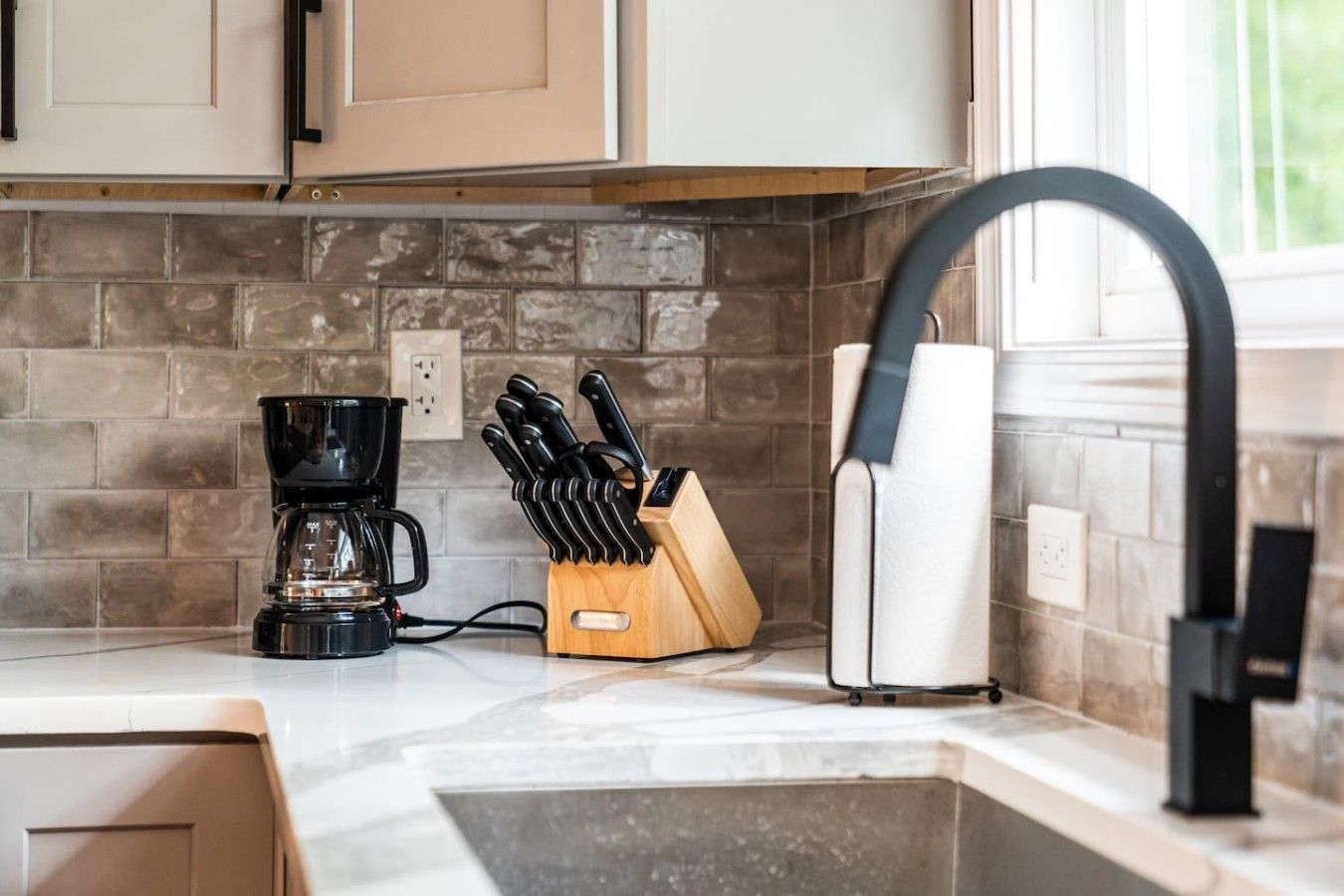 Une cuisine équipée d’une machine à café, d’un bloc à couteaux et d’un robinet moderne.