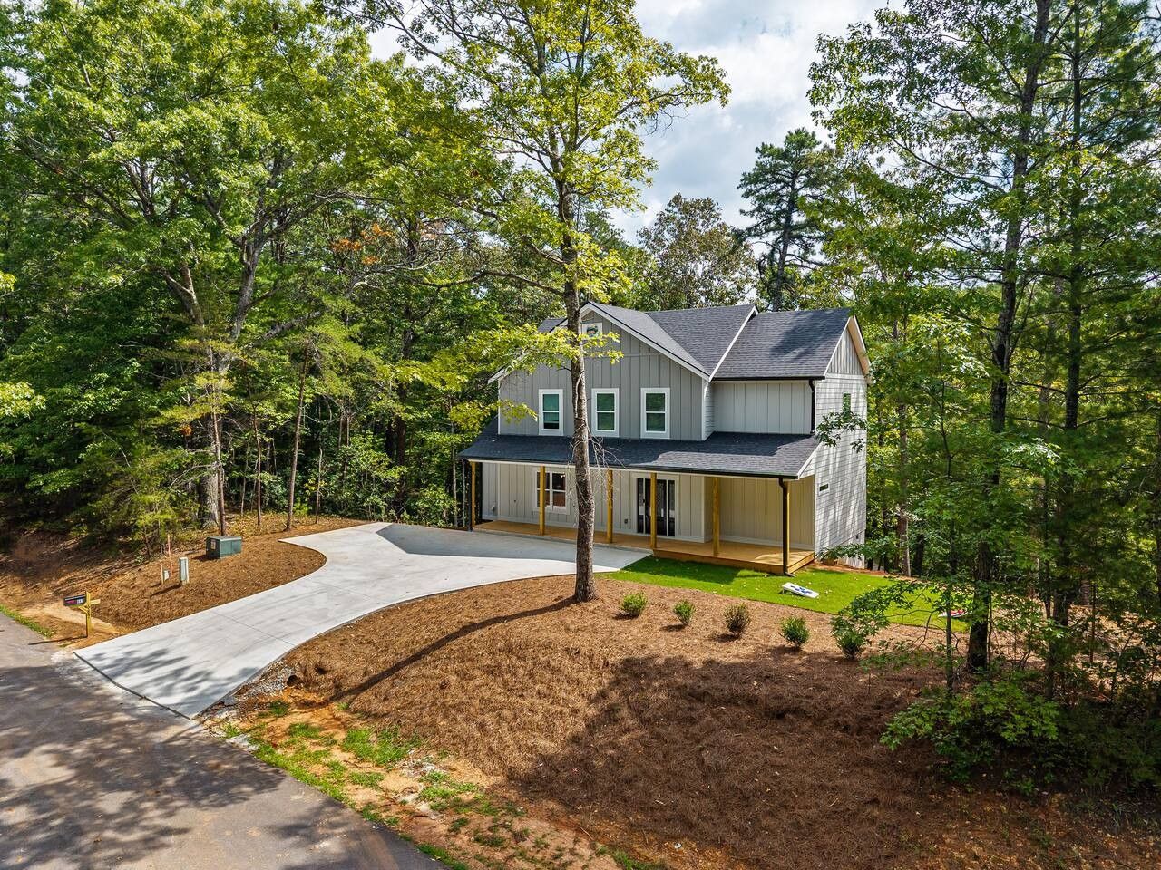 A two-story house with a covered porch, surrounded by a landscaped yard and trees.