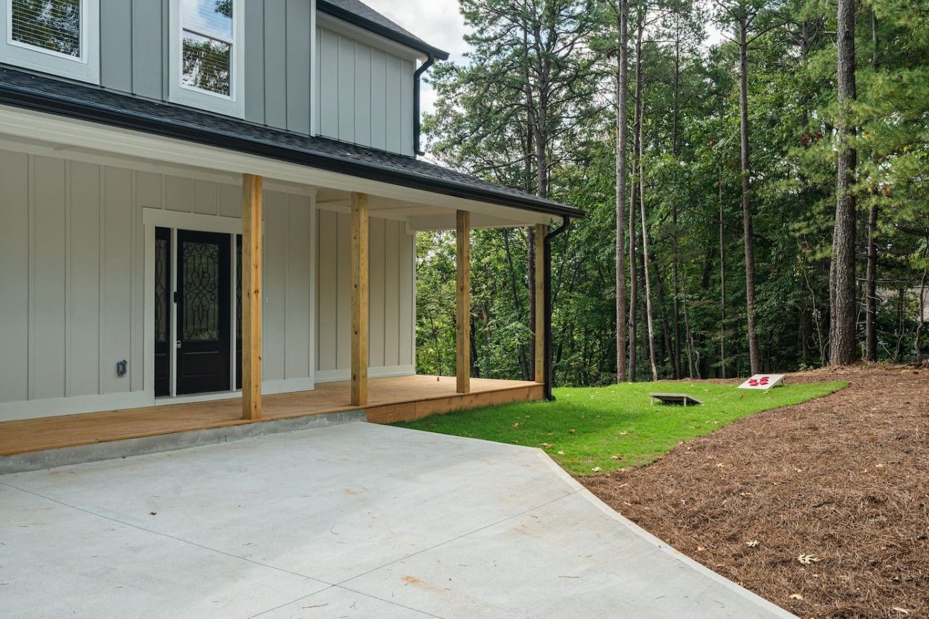 A modern two-story house with a covered porch and a well-maintained lawn.