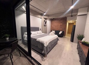 A modern bedroom with a large bed, a separate seating area, and a small table with chairs. - Modern & Cozy Apartment in North Bogotá (Bogotá)