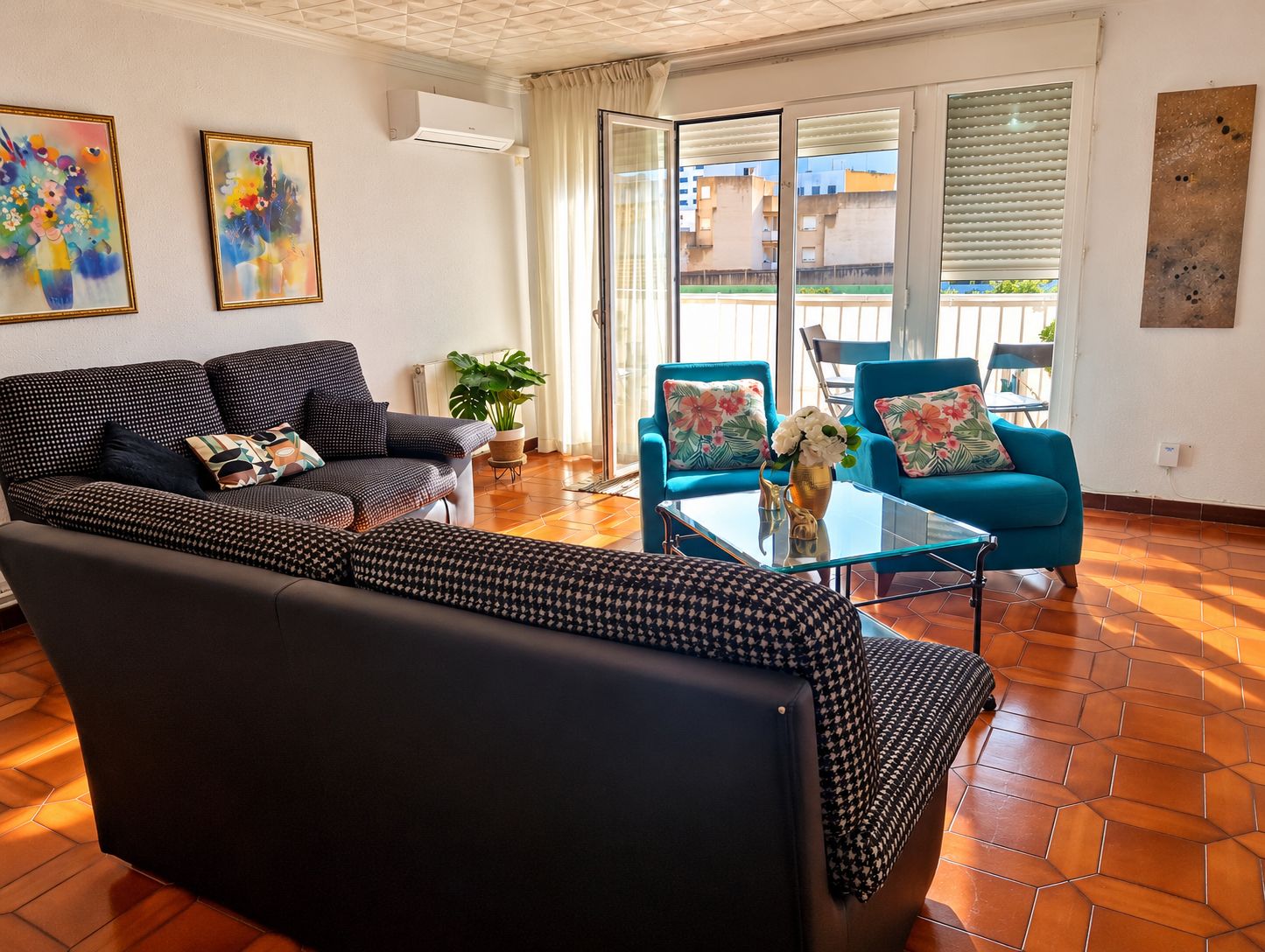 A living room with a sofa, a coffee table, and a blue armchair. There is a plant on the coffee table.